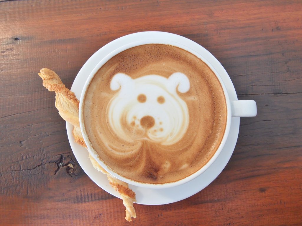 Latte Coffee art and biscuit stick on the wooden desk.